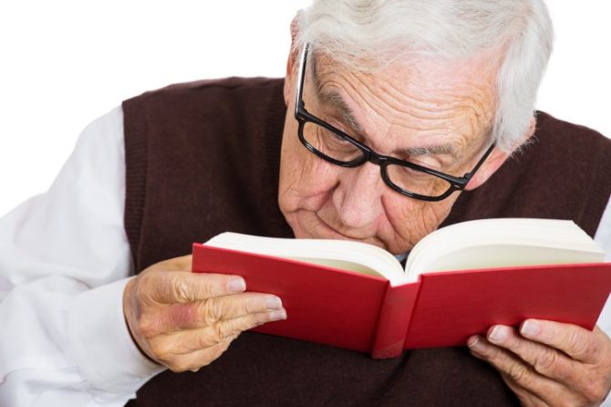 elderly man with macular degeneration and low vision reading with Microscope Eye Glasses