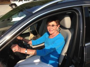 woman with macular degeneration sitting in her car, driving with low vision telescope glasses